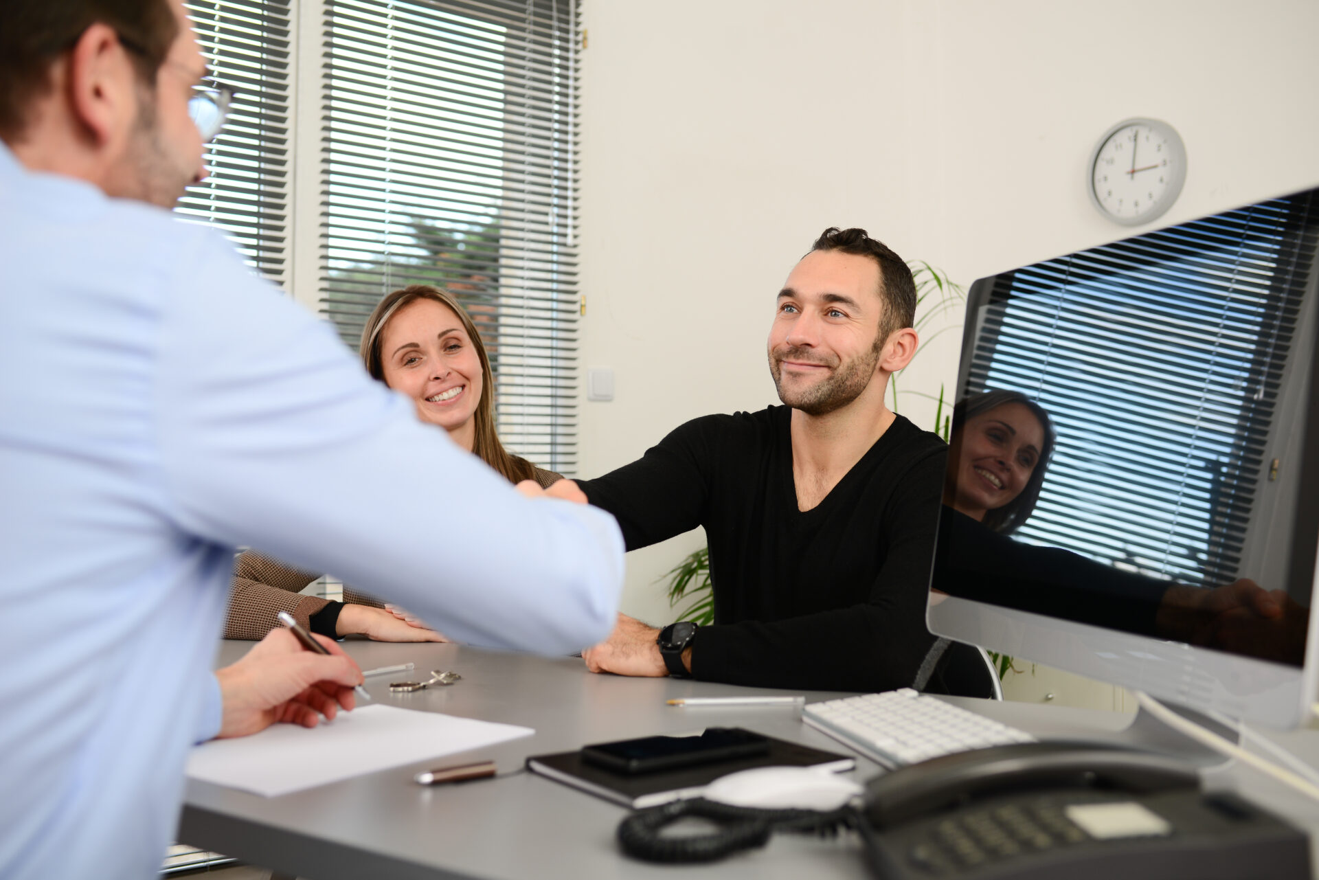 Couple shaking hands with an estate agent after discussing a property sale, representing house prices and seller demand in Guiseley.