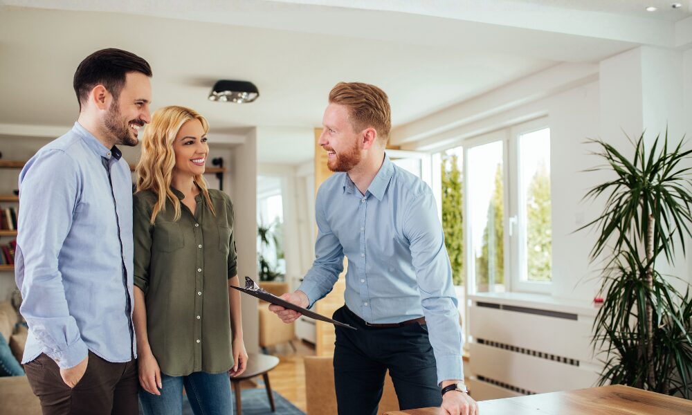 Estate agent welcoming a couple during a property viewing in a bright, modern home, illustrating the home buying and renting opportunities available when living in Polesworth B78.