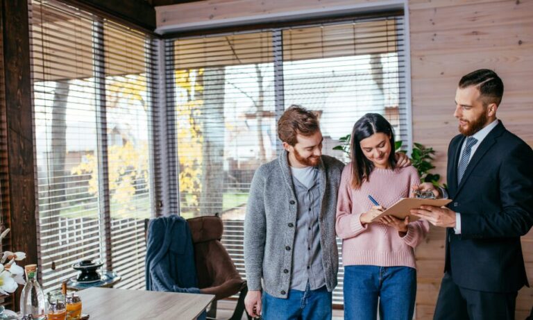 An estate agent meeting with a young couple as they sign property documents, illustrating the home buying process in Seven Dials BN1 and supporting the area guide for buyers, renters and investors.