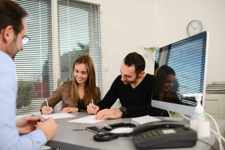 Couple signing property documents with an estate agent, representing selling a home in Wigan’s fast-moving property market.