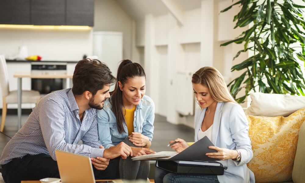 A Belvoir St Helens estate agent discusses property options with a couple in a modern home, illustrating the home buying or renting process featured in the Living in Rainhill L35 area guide.