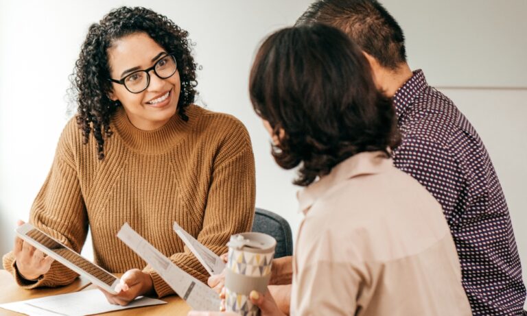 A letting agent explains tenancy documents and renters' rights to prospective tenants during a meeting, illustrating the guidance and support available under the Renters' Rights Act 2026 in Wigan.
