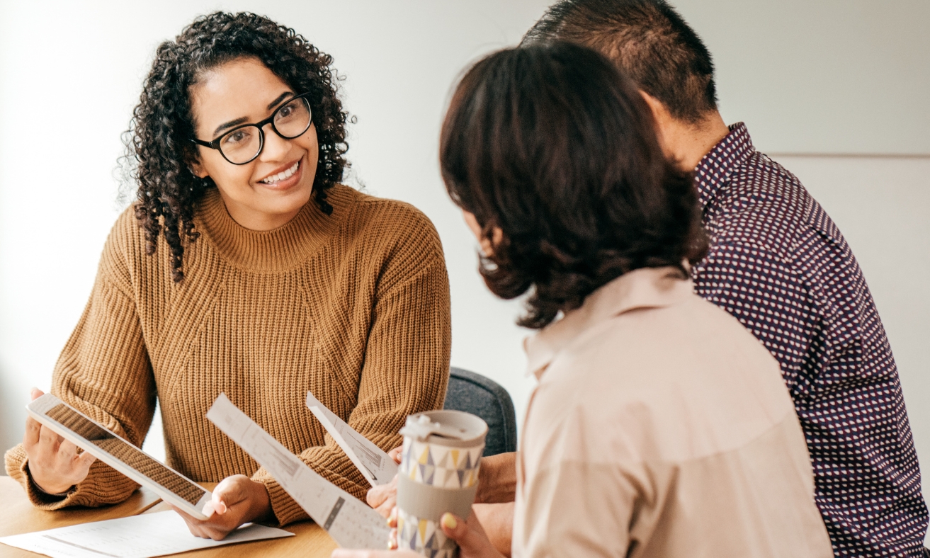 A letting agent explains tenancy documents and renters' rights to prospective tenants during a meeting, illustrating the guidance and support available under the Renters' Rights Act 2026 in Wigan.