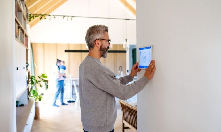 Homeowner using a smart heating control in an energy-efficient property, representing EPC upgrades for rental homes in Northwich.