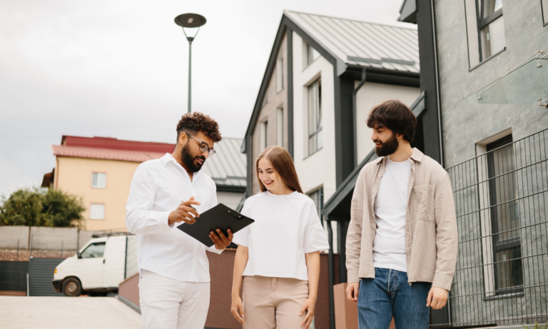 Letting agent discussing a rental property with young tenants outside a modern home