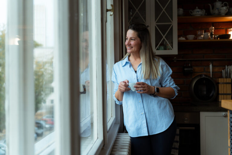 Woman enjoying a cup of coffee by the window in a modern rental home